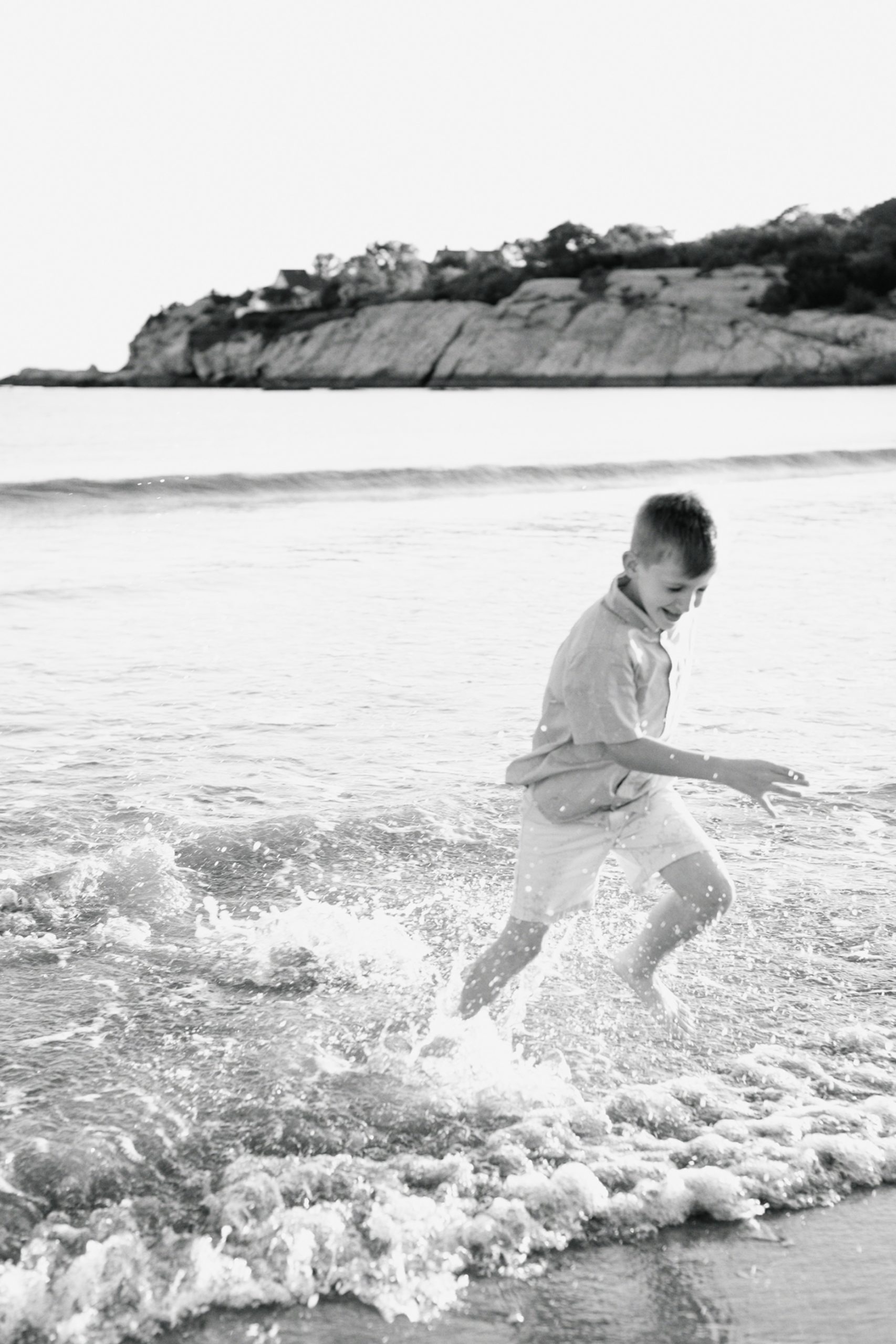 Little boy running out of the beach during outdoor family photo session.