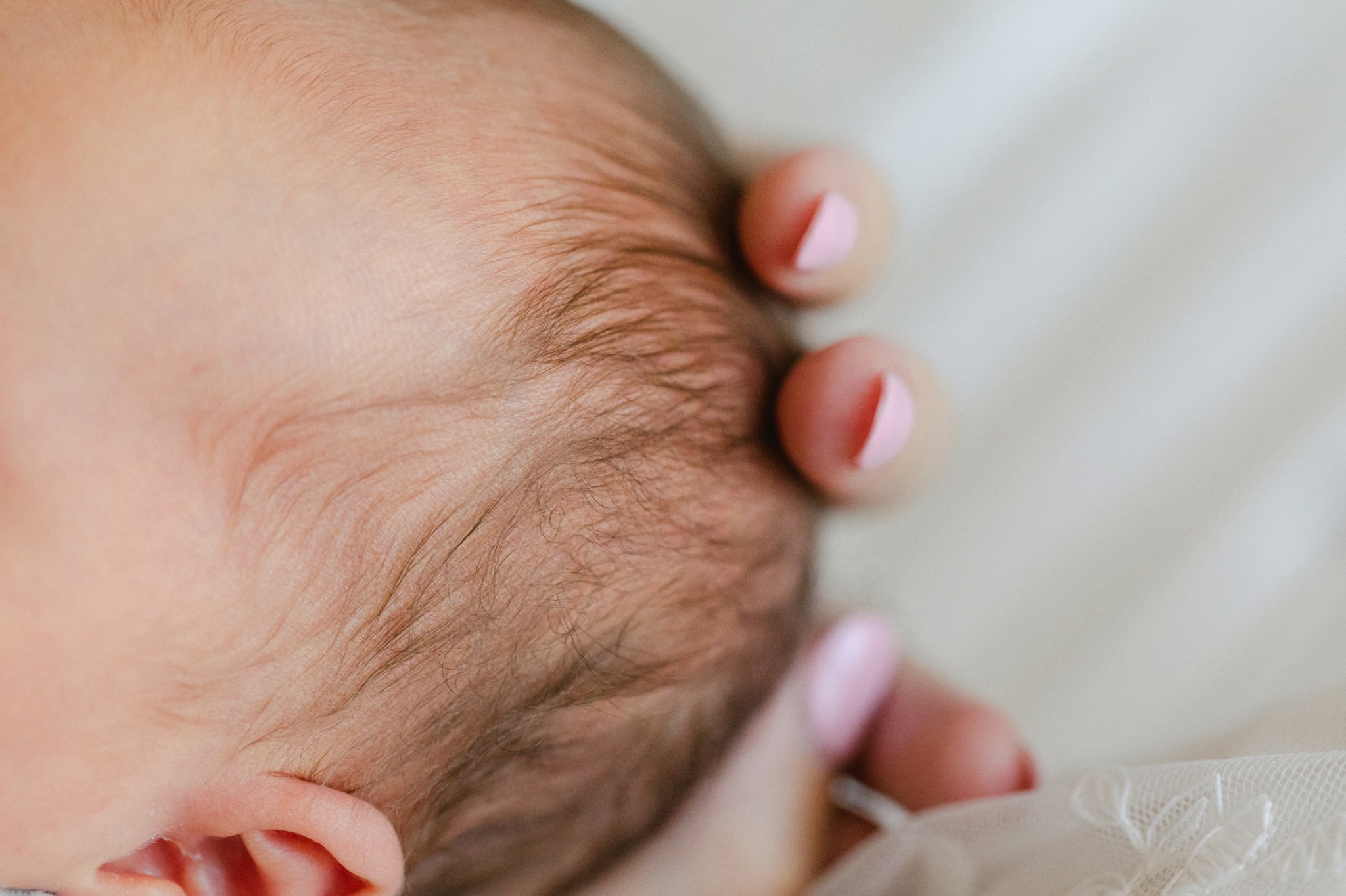 Image of baby hair being held by mothers hands.